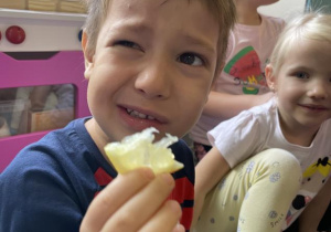 dziecko próbuje się uśmiechać podczas jedzenia cytryny